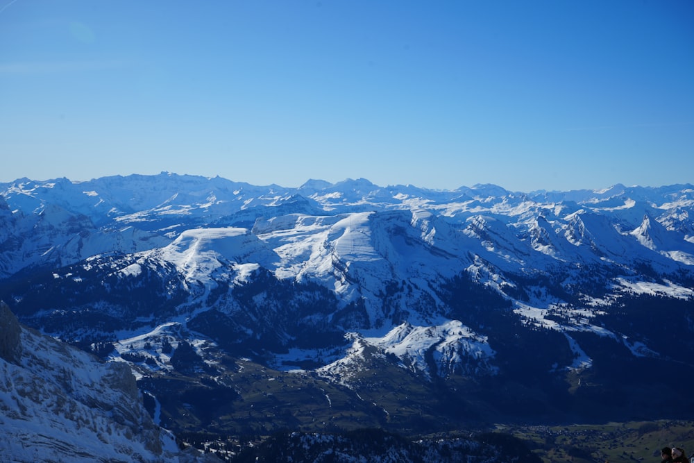 a view of a snowy mountain range from the top of a mountain