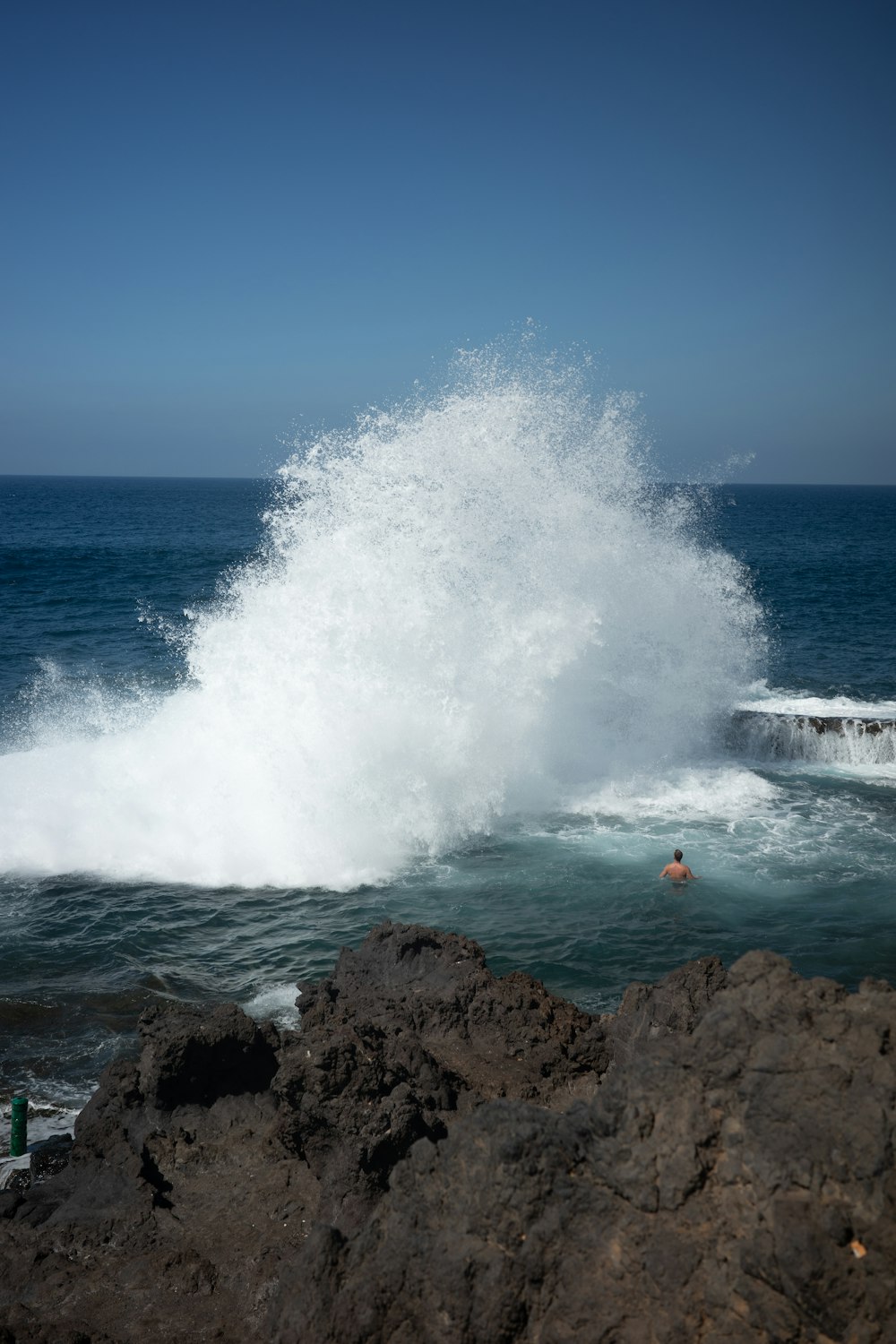 a person swimming in the ocean near a large wave