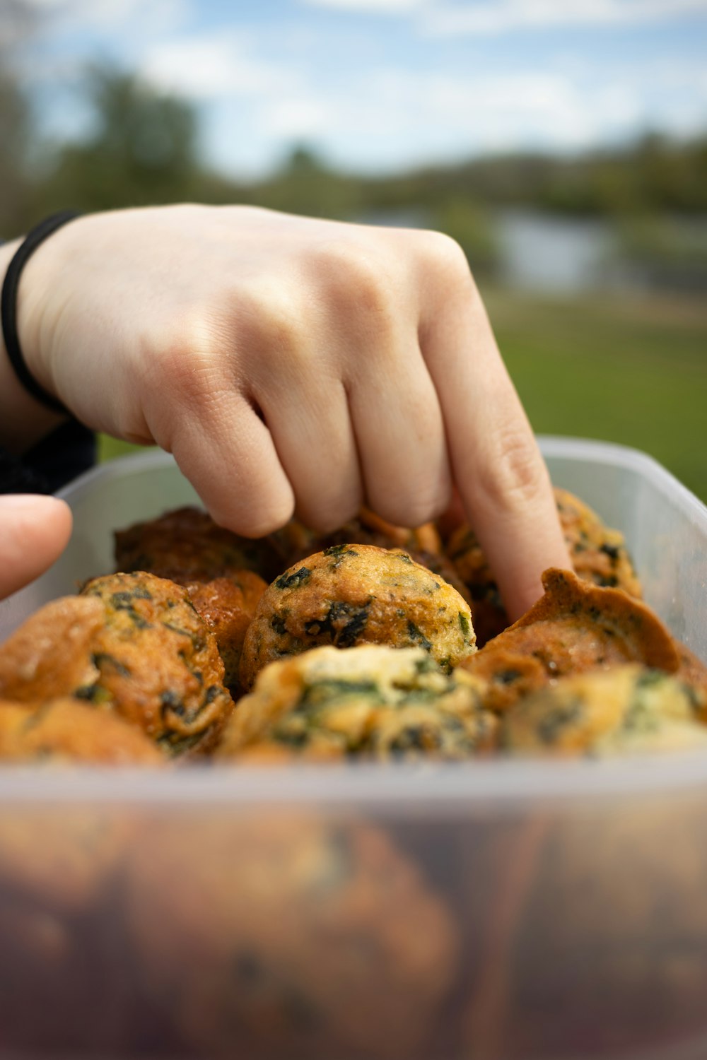 a close up of a person picking up food from a container