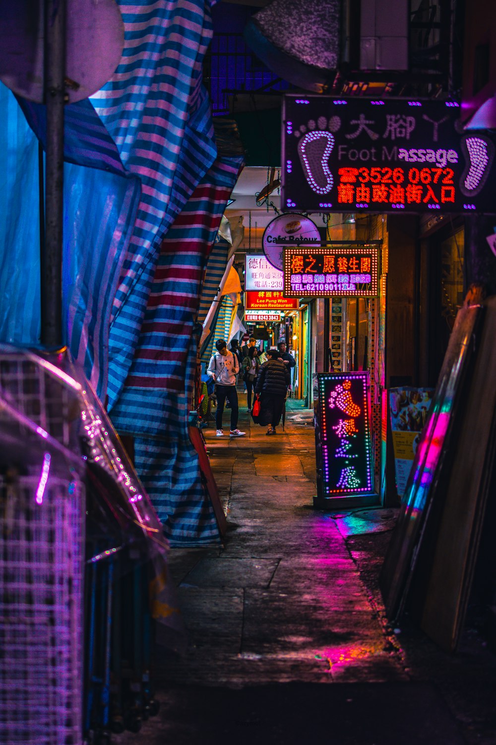 a narrow alleyway with neon lights and signs
