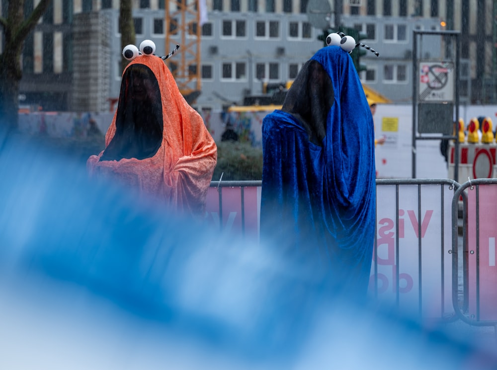 two people dressed in blue and orange standing next to each other