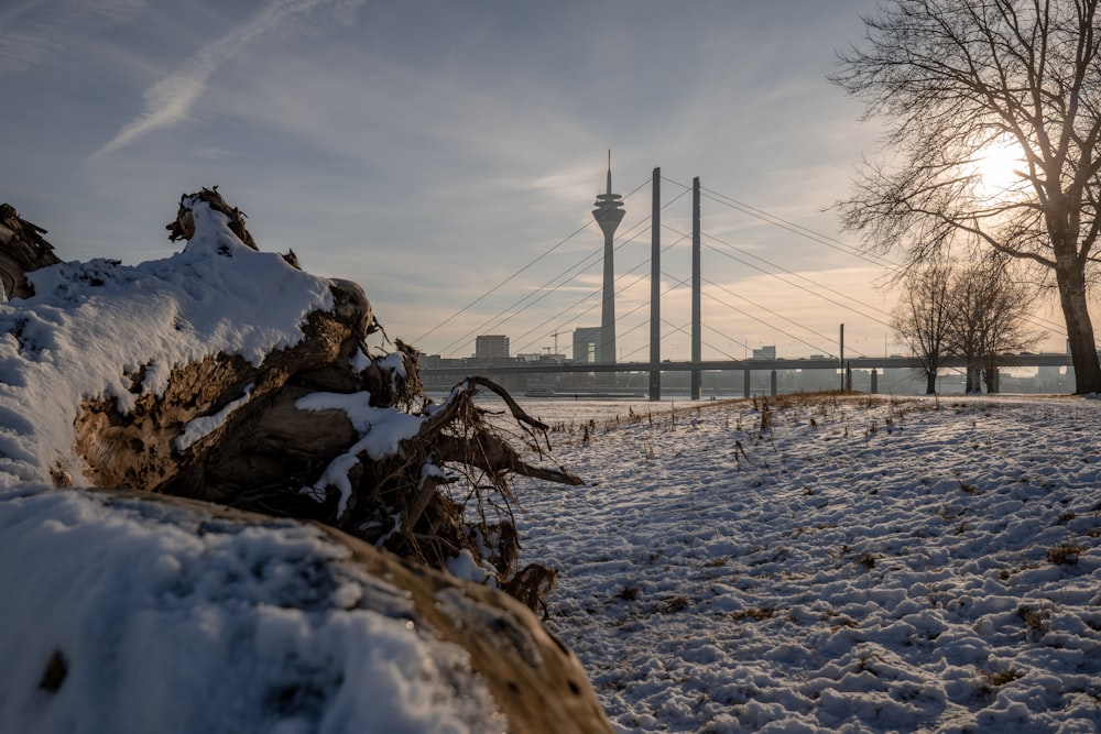 a snow covered field with a bridge in the background