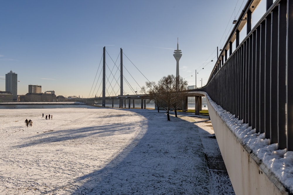 a snow covered field with a bridge in the background