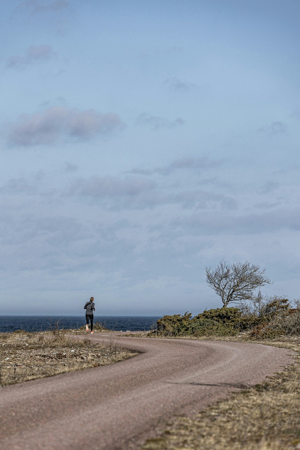uma pessoa em pé em uma estrada de terra perto do oceano