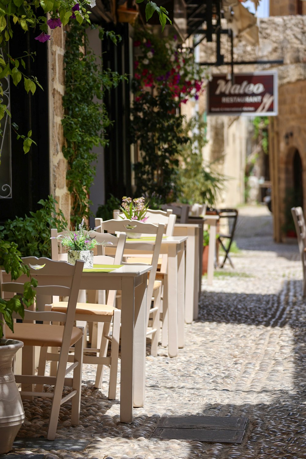 a row of tables and chairs on a cobblestone street