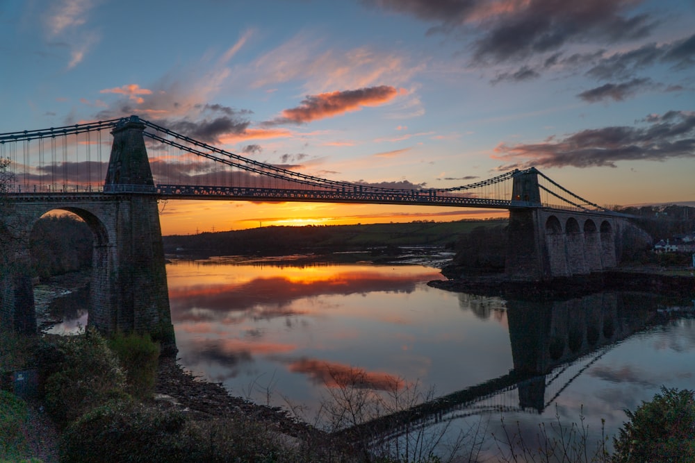 a bridge over a body of water with a sunset in the background