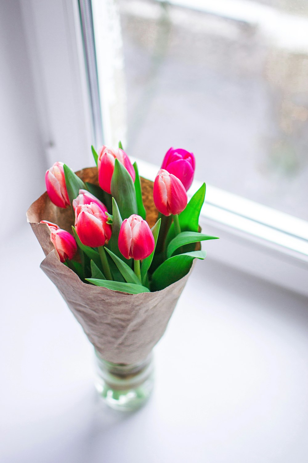a bouquet of tulips in a vase on a window sill