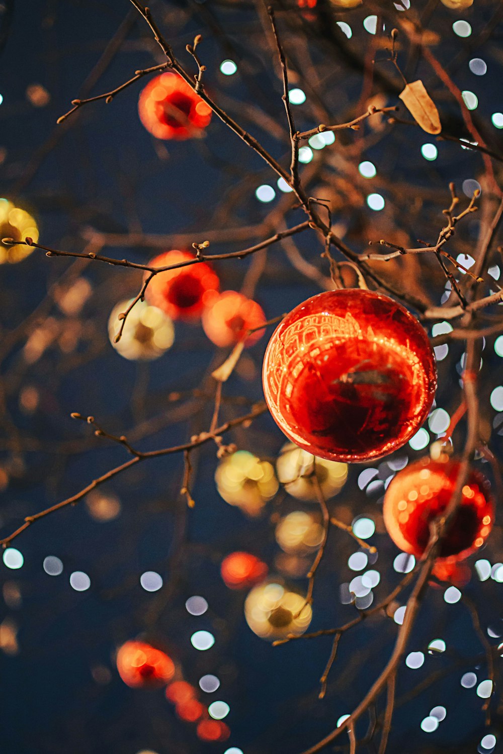a red ornament hanging from a tree with lights in the background