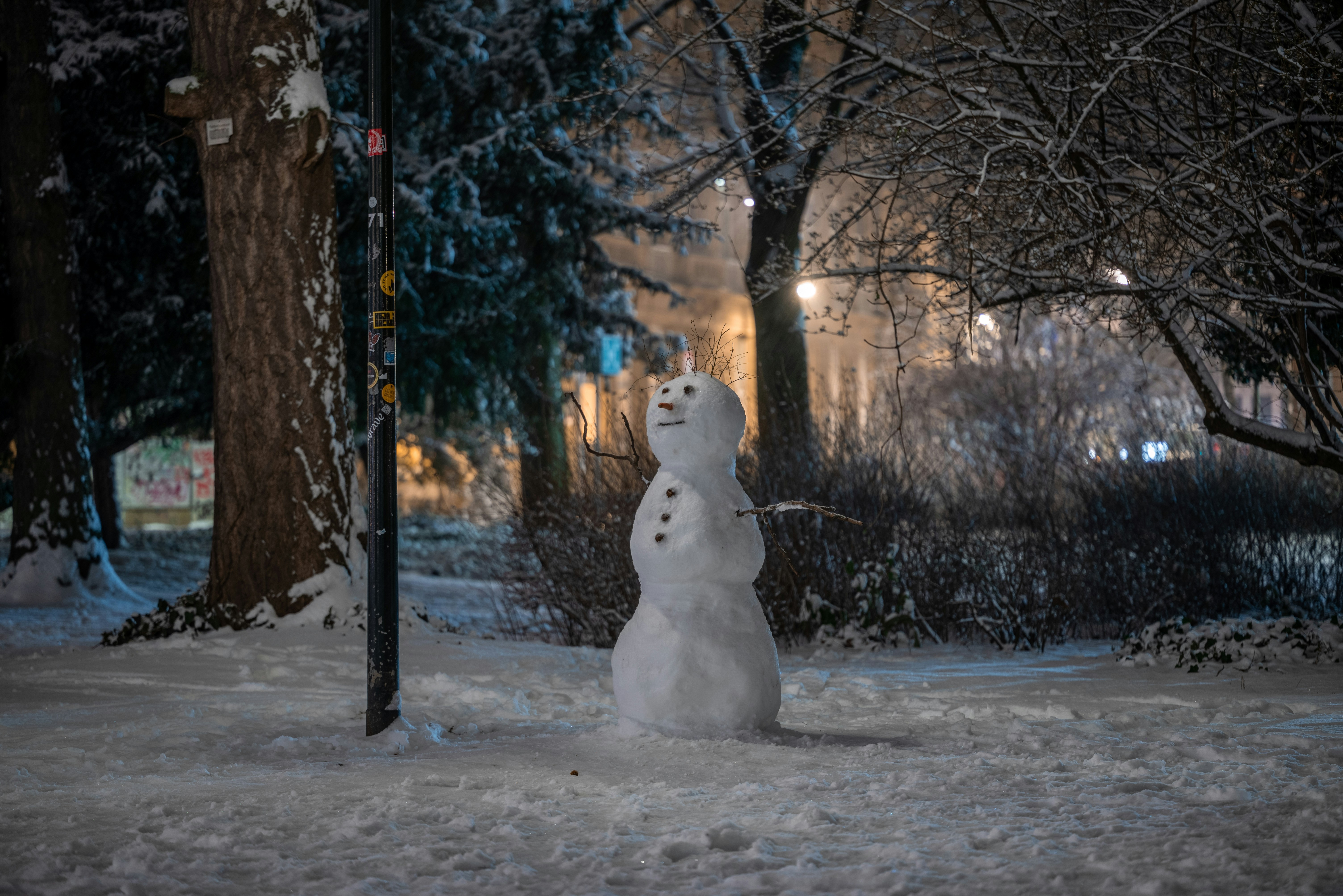 Ein Schneemann steht neben einer Straßenlaterne