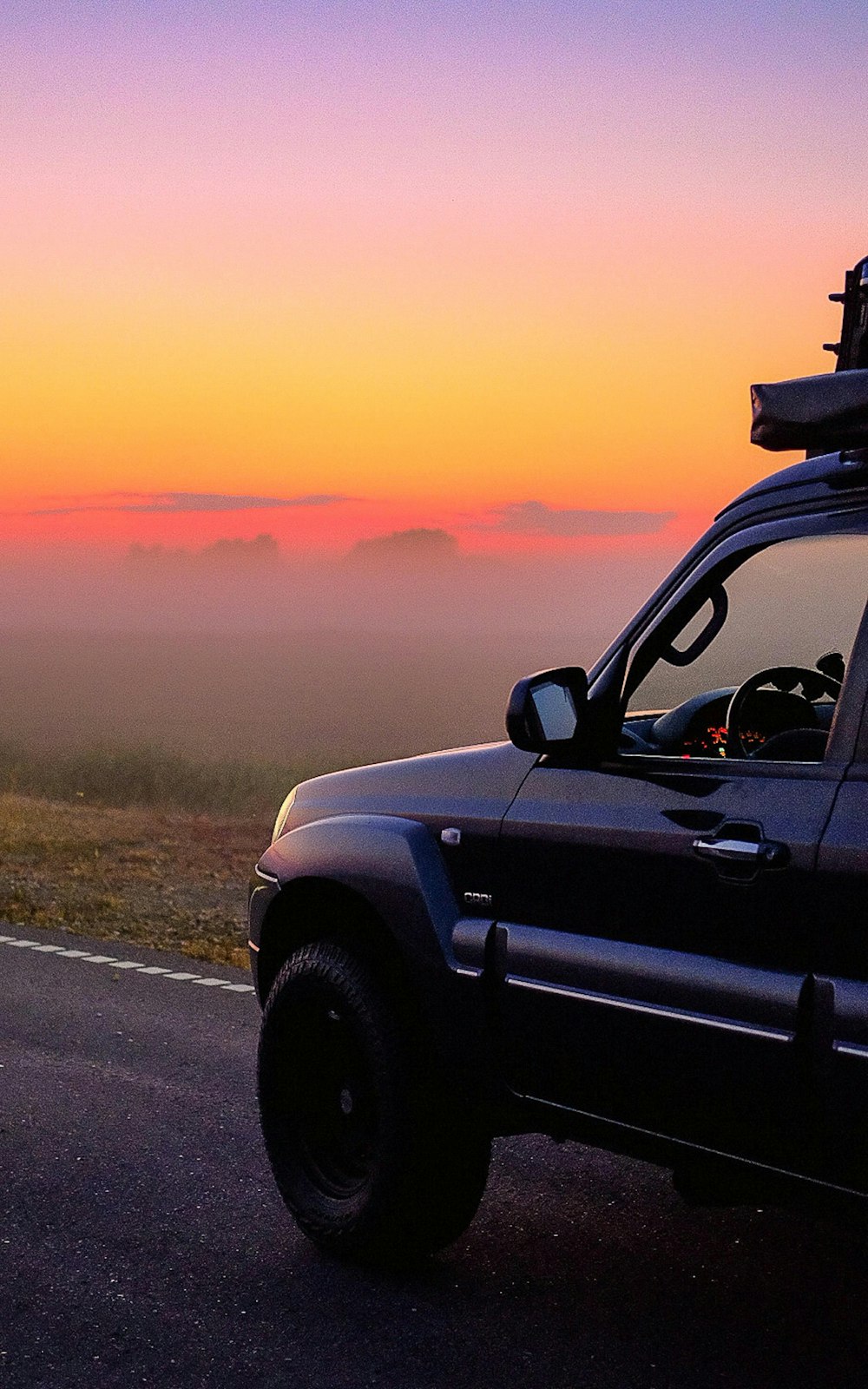 a truck parked on the side of a road with a sunset in the background