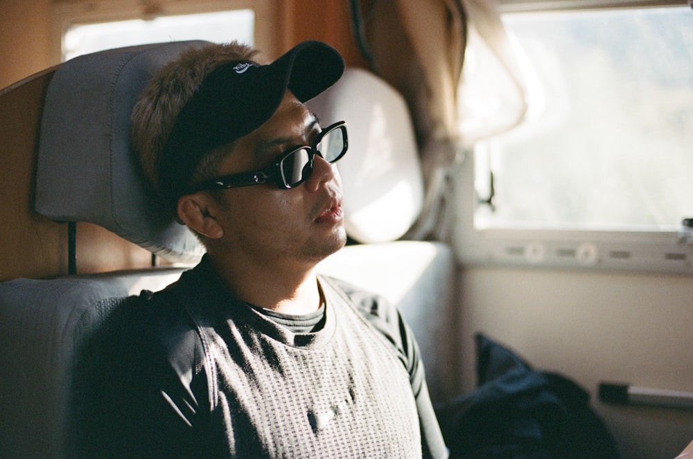 a man wearing glasses and a hat on a train