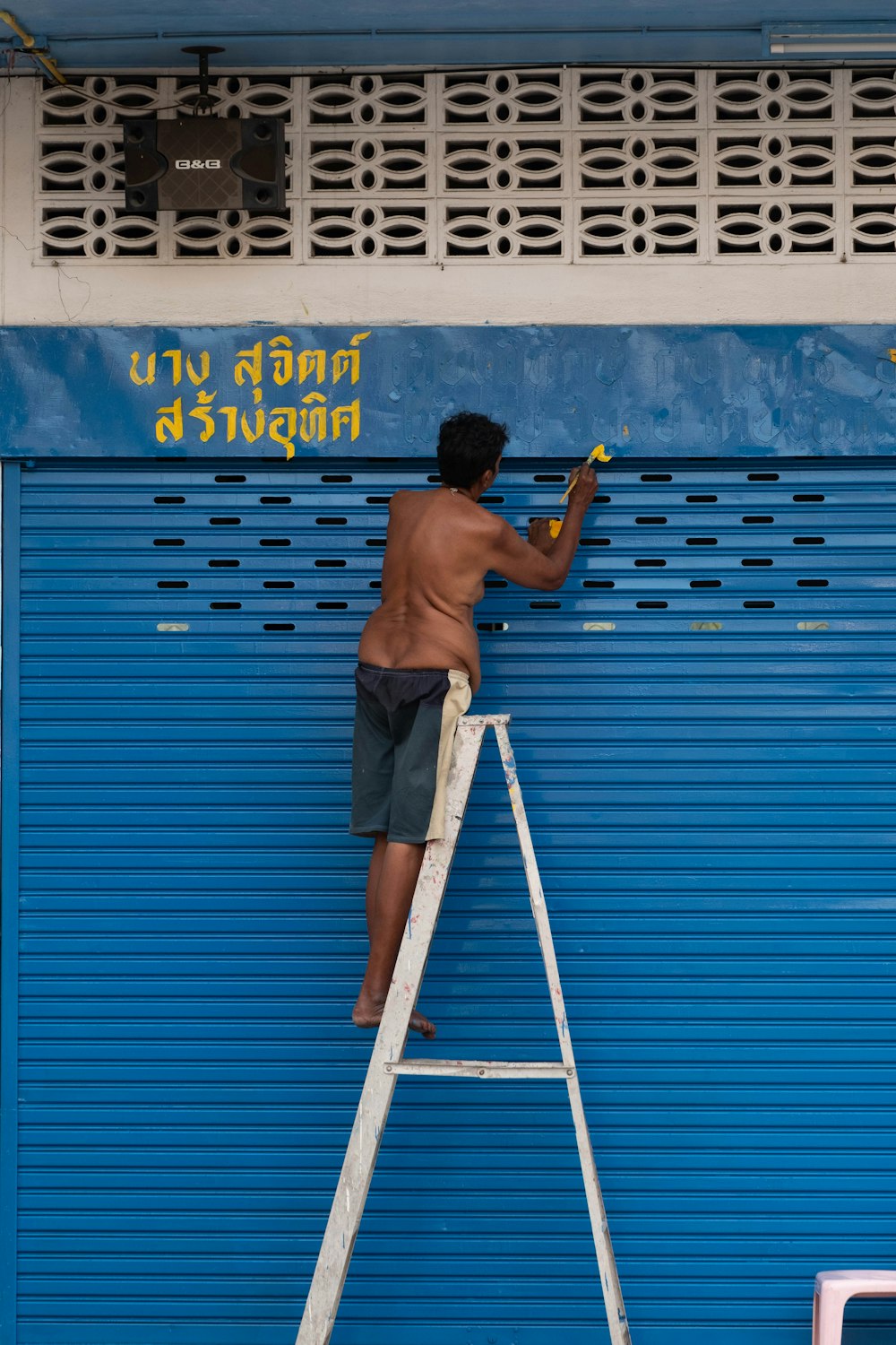 a man on a ladder painting a blue wall