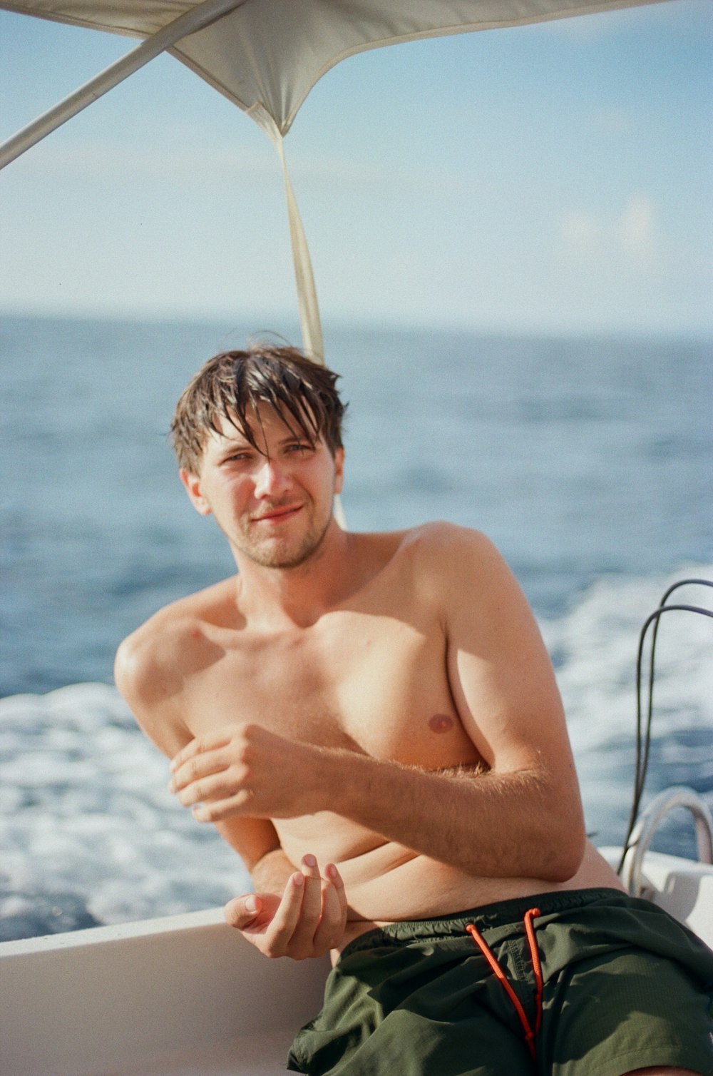Ein Mann ohne Hemd sitzt auf einem Boot im Meer