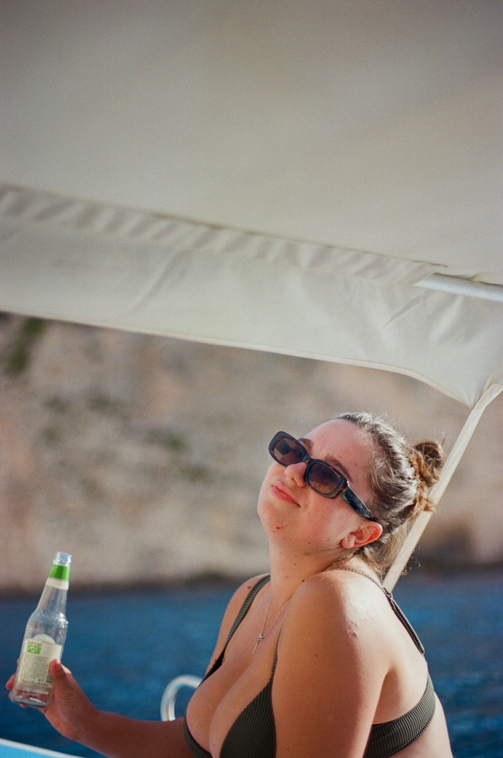 eine Frau im Bikini mit einer Wasserflasche in der Hand