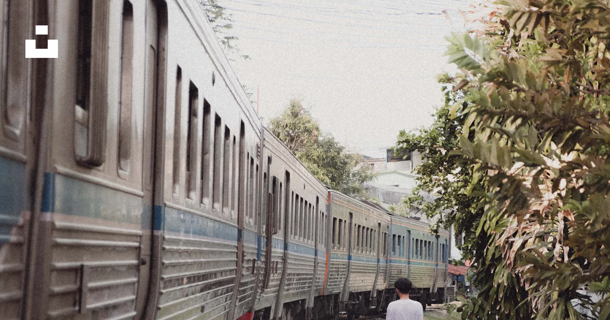 A person walking down a path next to a train photo – Free Human Image ...