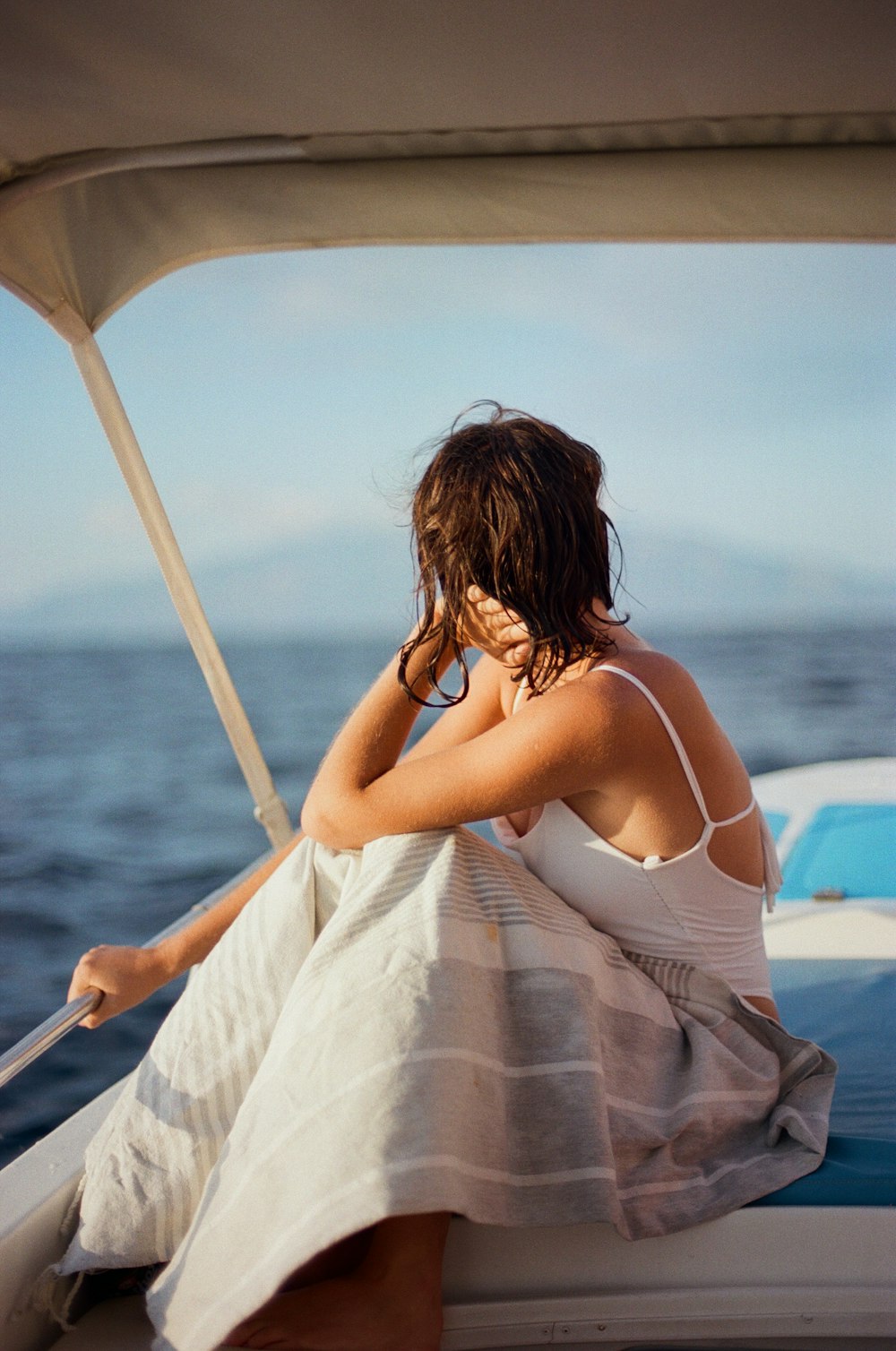 a woman in a white dress sitting on a boat