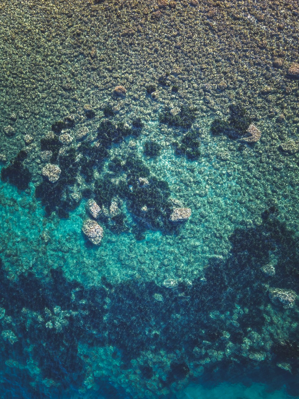 an aerial view of the ocean with rocks and water