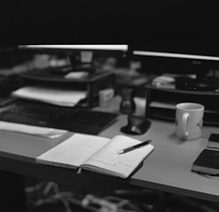 a desk with a laptop, keyboard, and a cup of coffee
