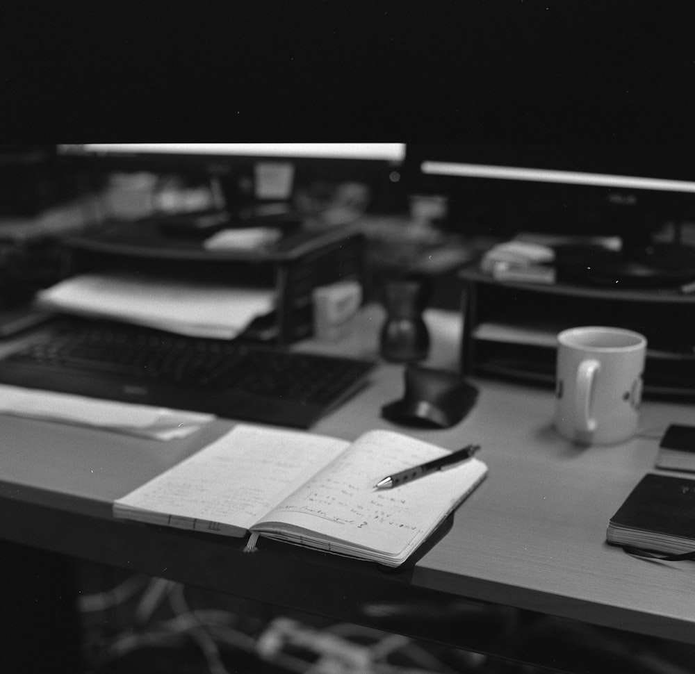 a desk with a laptop, keyboard, and a cup of coffee