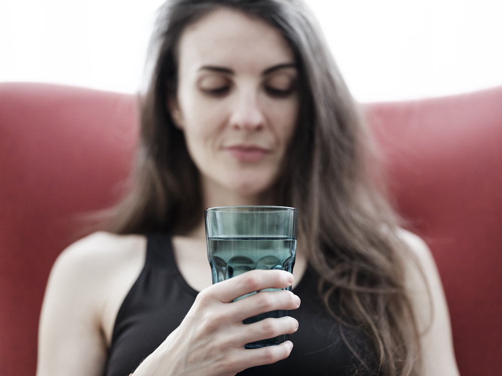 a woman sitting on a couch holding a glass of water