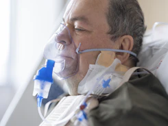 a man laying in a hospital bed with an oxygen tube attached to his face