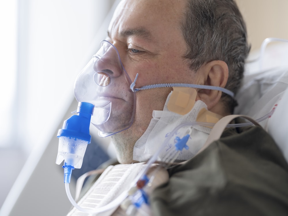 a man laying in a hospital bed with an oxygen tube attached to his face