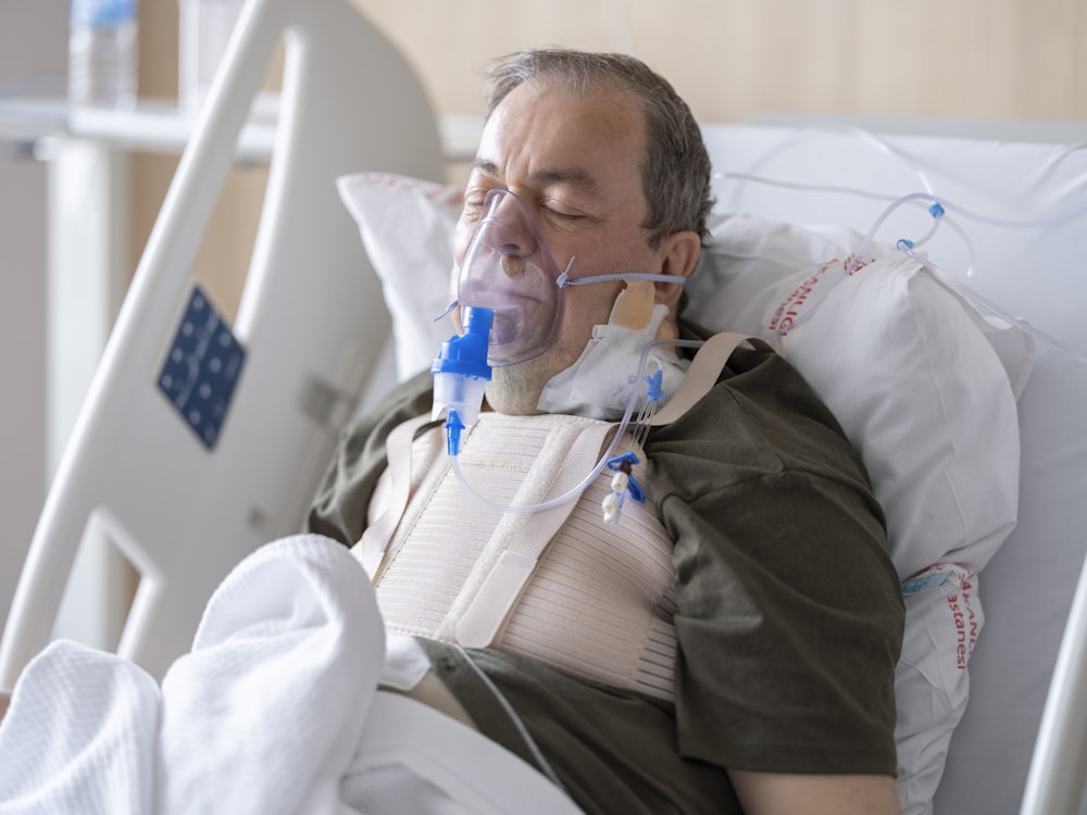 a man laying in a hospital bed with oxygen in his mouth