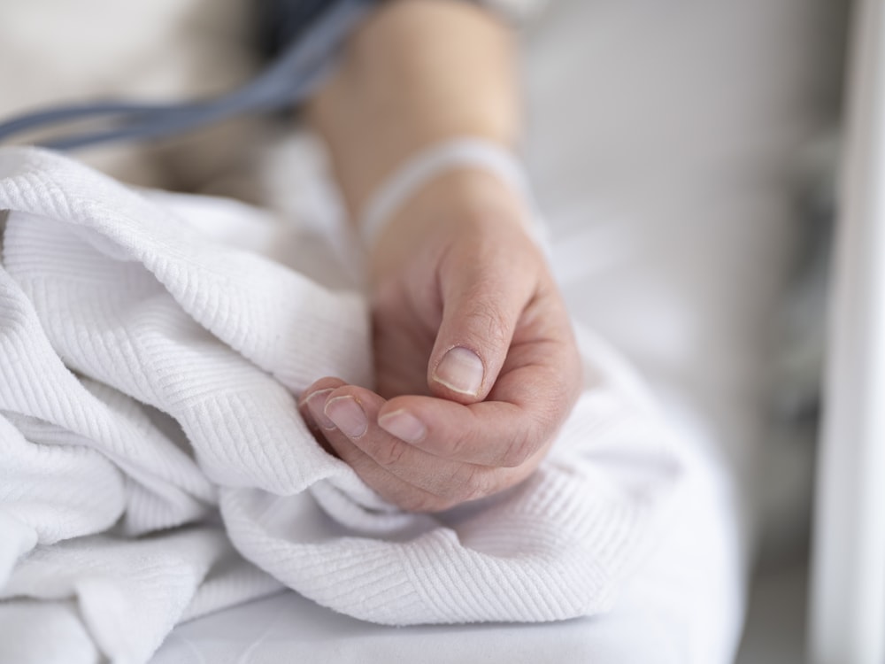 a person with a bandage on their hand sitting on a bed