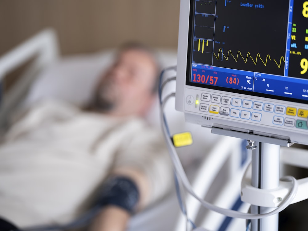 a man laying in a hospital bed next to a monitor