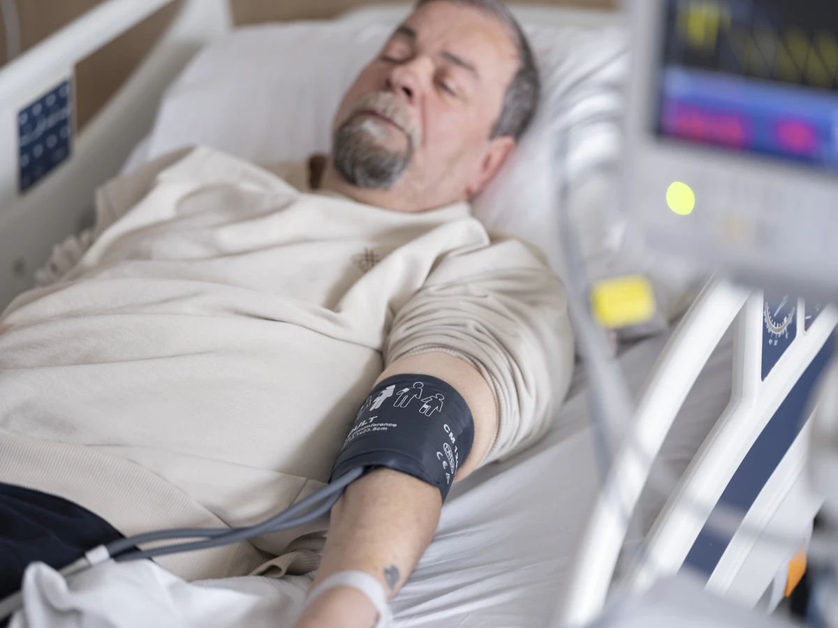 Man receiving an intravenous vitamin and mineral infusion in a clinical setting with a nurse checking his vitals.