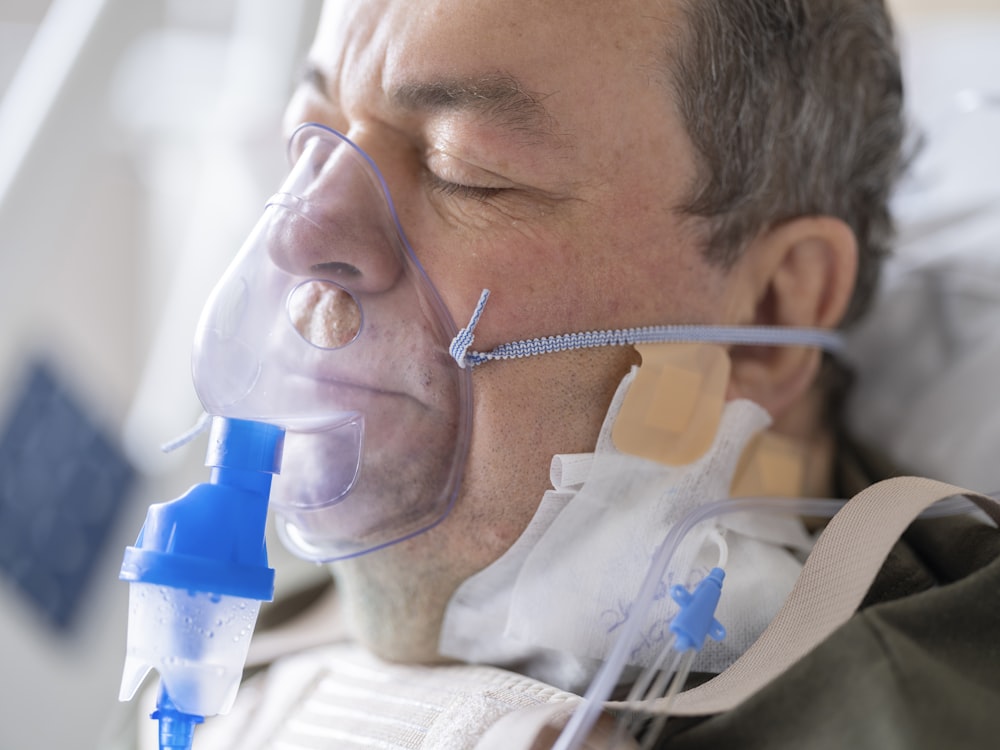 a man laying in a hospital bed with an oxygen tube attached to his face
