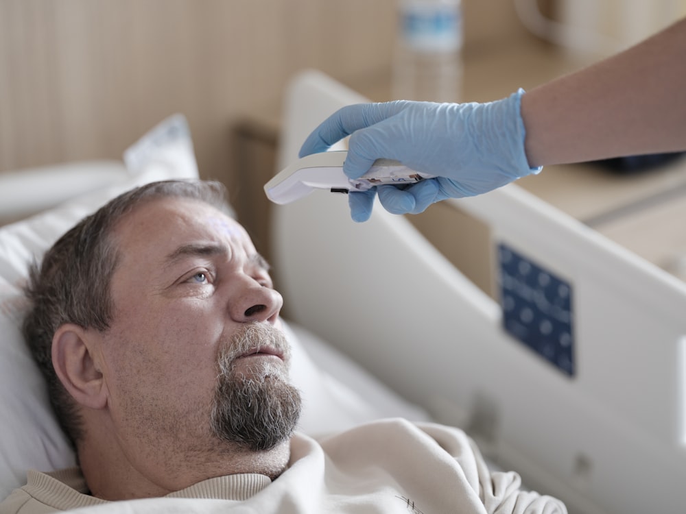 a man laying in a hospital bed with a thermometer in his hand