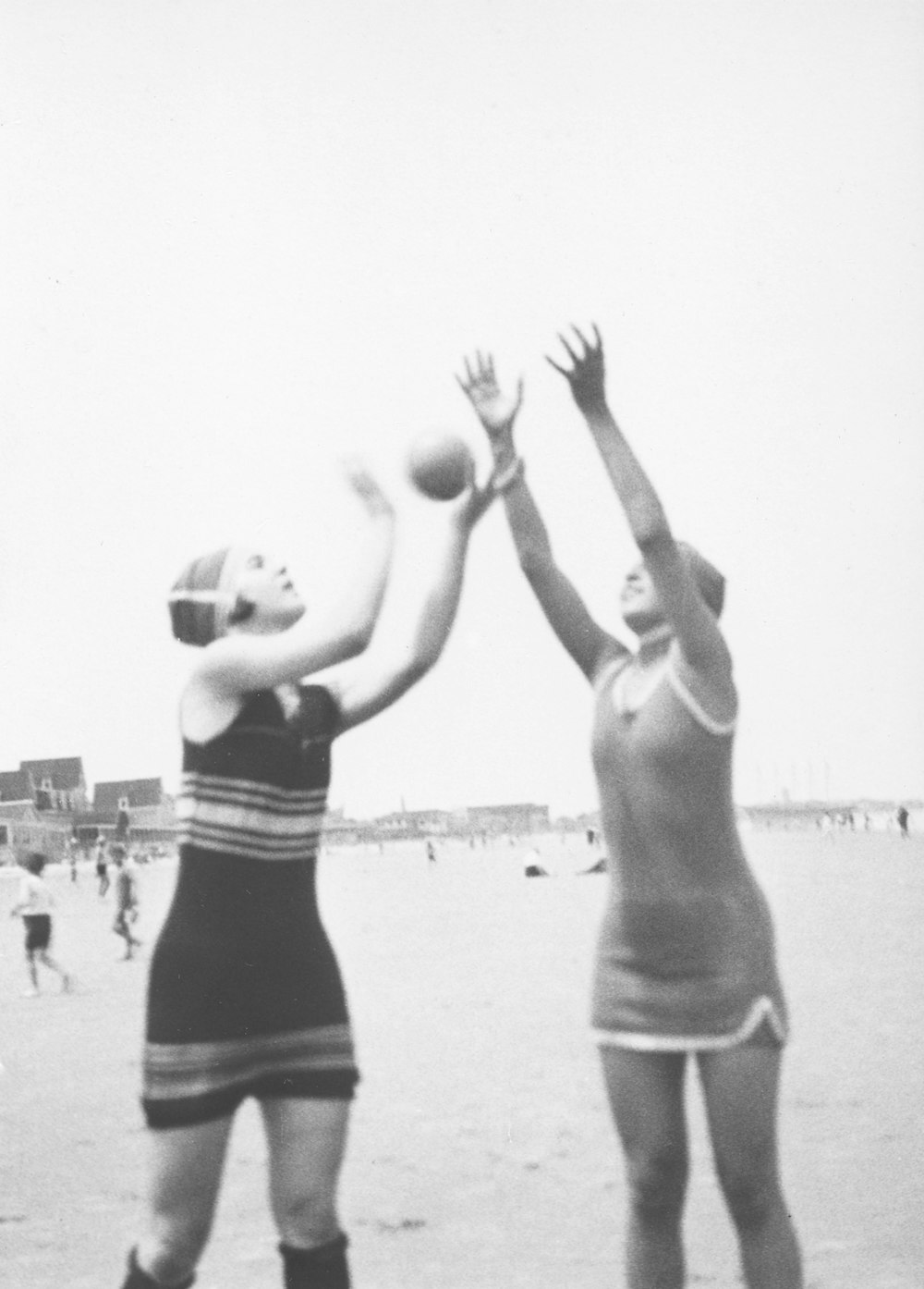 two women reaching for a frisbee on the beach