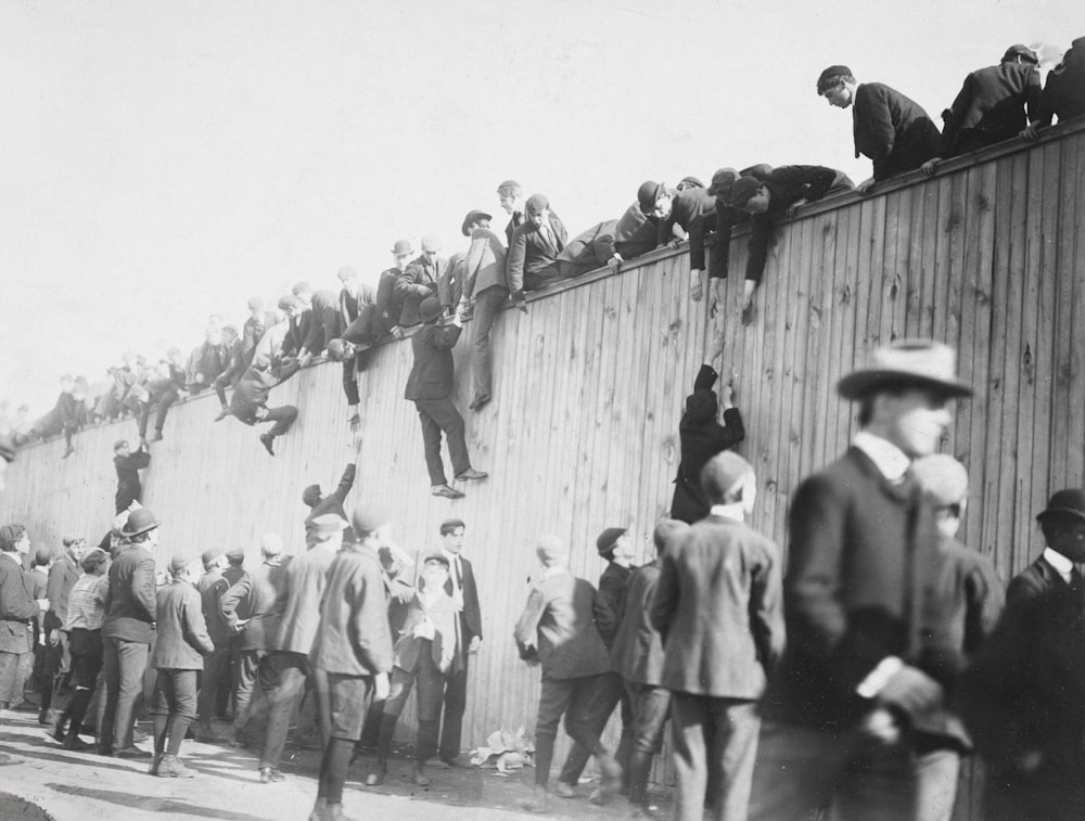 a crowd of people standing on top of a wooden wall