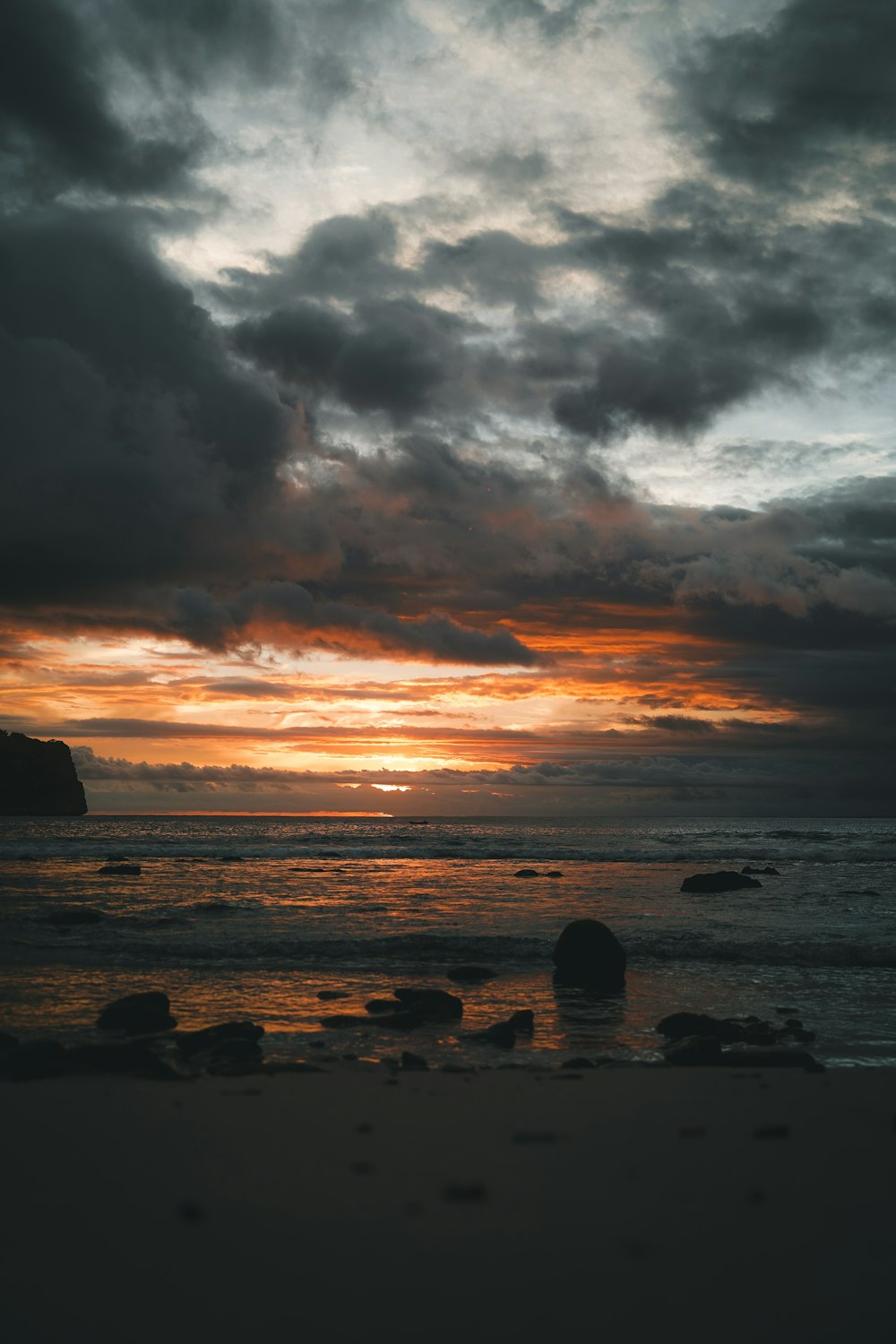 the sun is setting over the ocean on a cloudy day