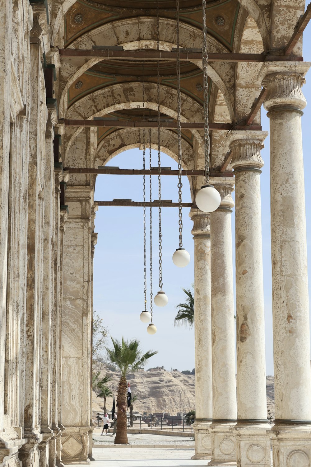 a stone building with columns and a chandelier hanging from it's ceiling