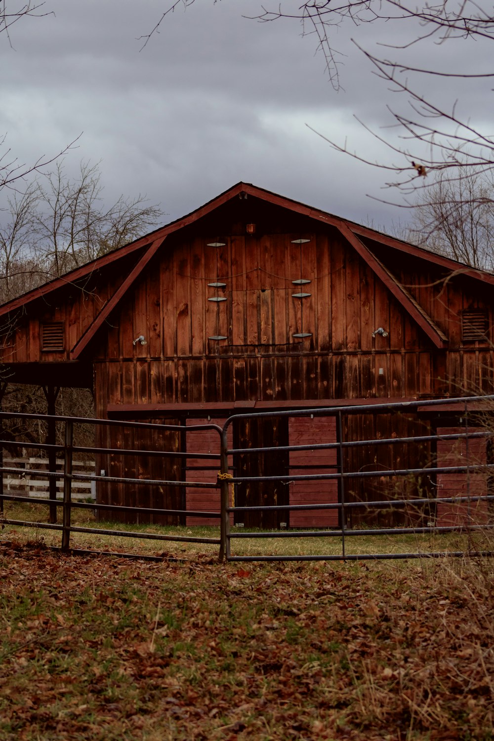 a barn with a gate and a wooden building in the background