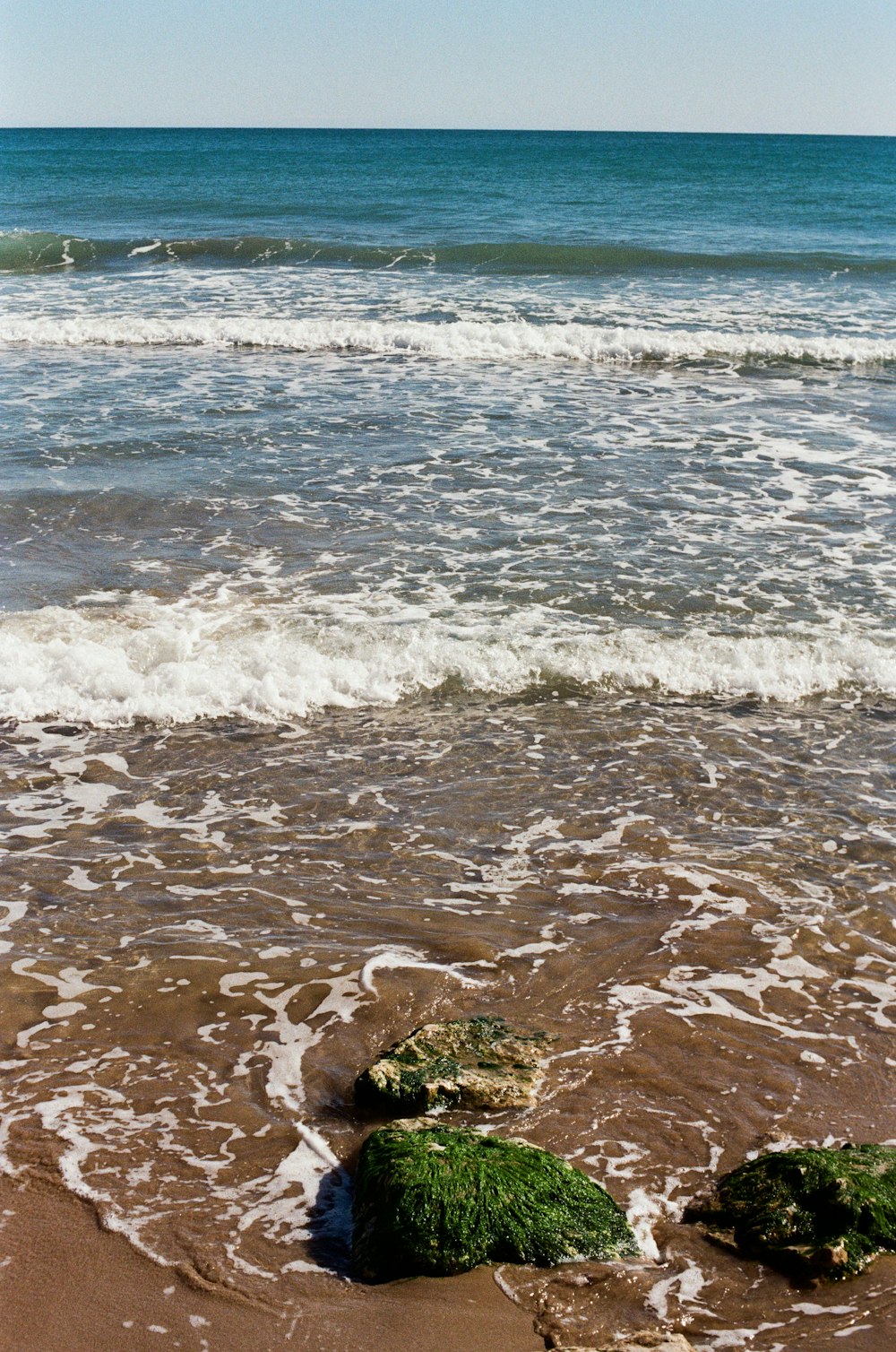 a couple of rocks sitting on top of a sandy beach