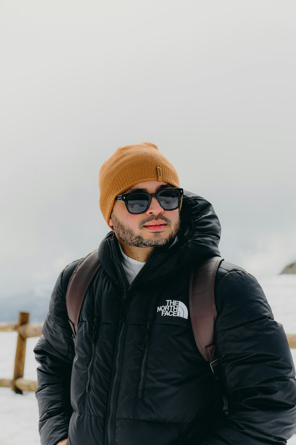 a man in a black jacket and a brown hat