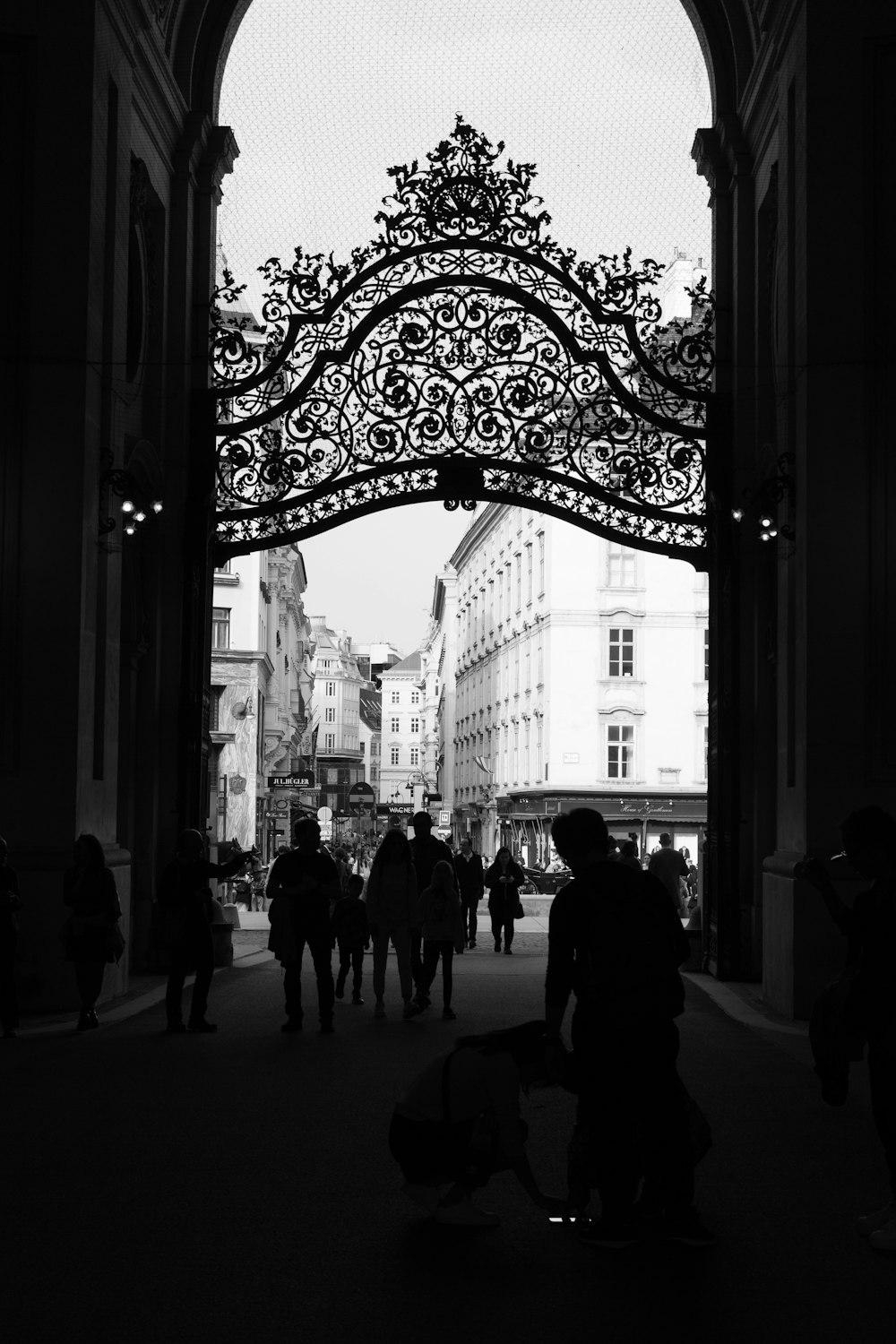 a black and white photo of people walking under a gate