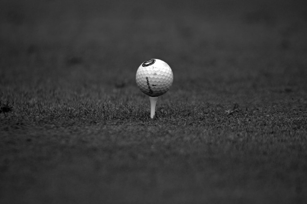a black and white photo of a golf ball on a tee