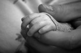 une photo en noir et blanc d'une main d'adulte tenant une main d'enfant