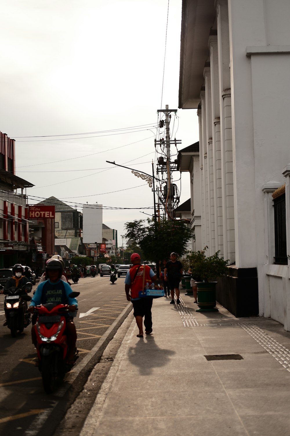 a couple of people walking down a street next to a motorcycle