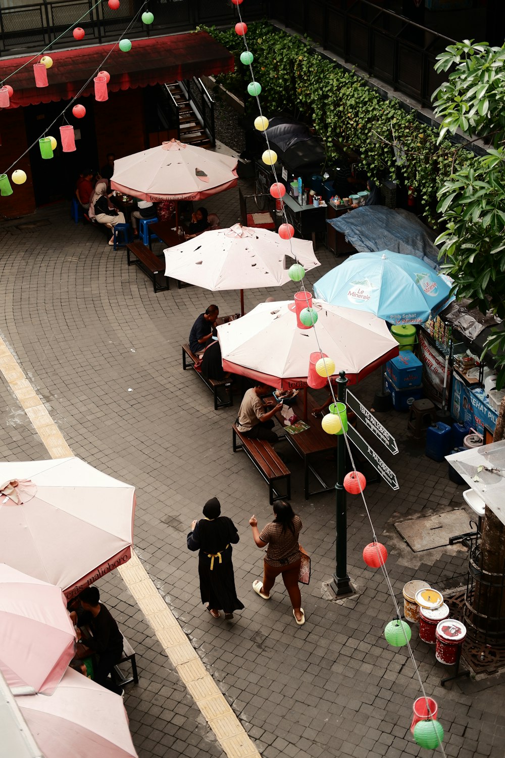 a group of people standing around tables with umbrellas