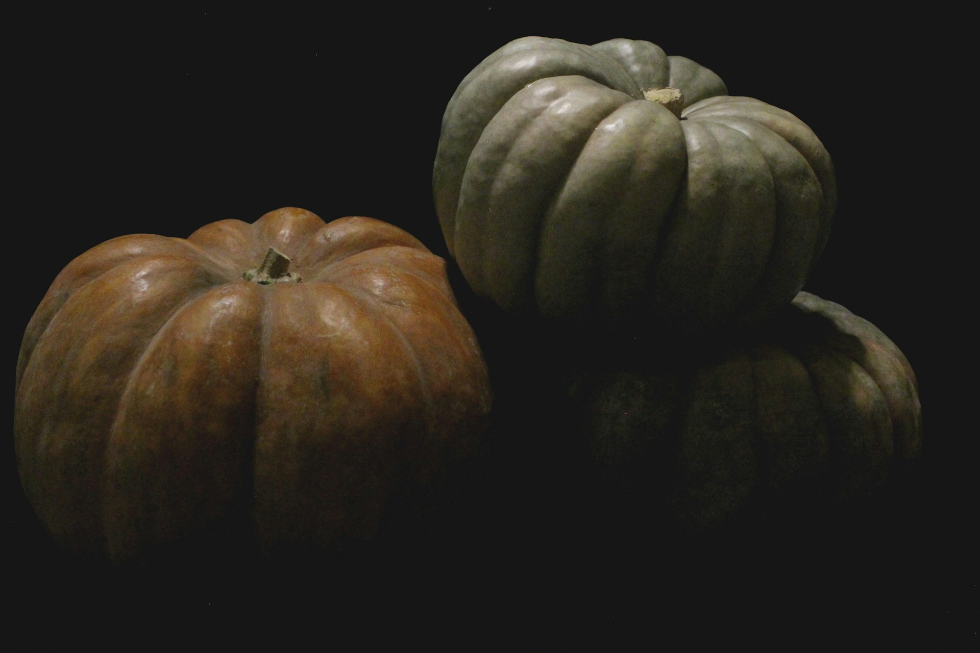 three pumpkins sitting side by side on a black background