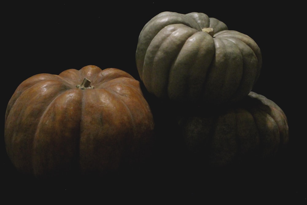 three pumpkins sitting side by side on a black background