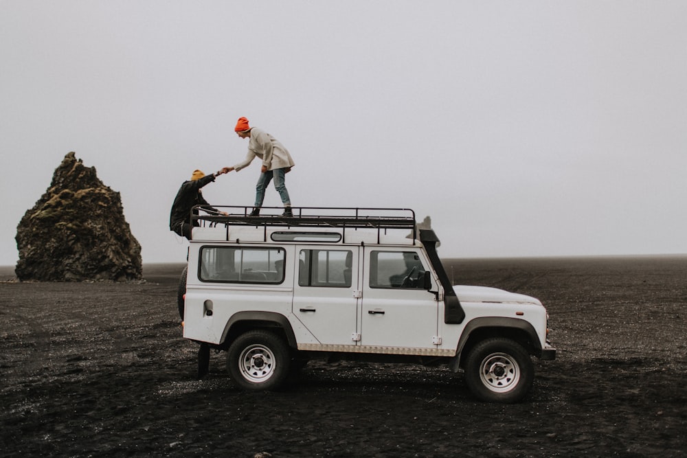 a man standing on top of a white jeep