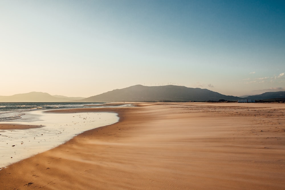 a sandy beach with mountains in the distance