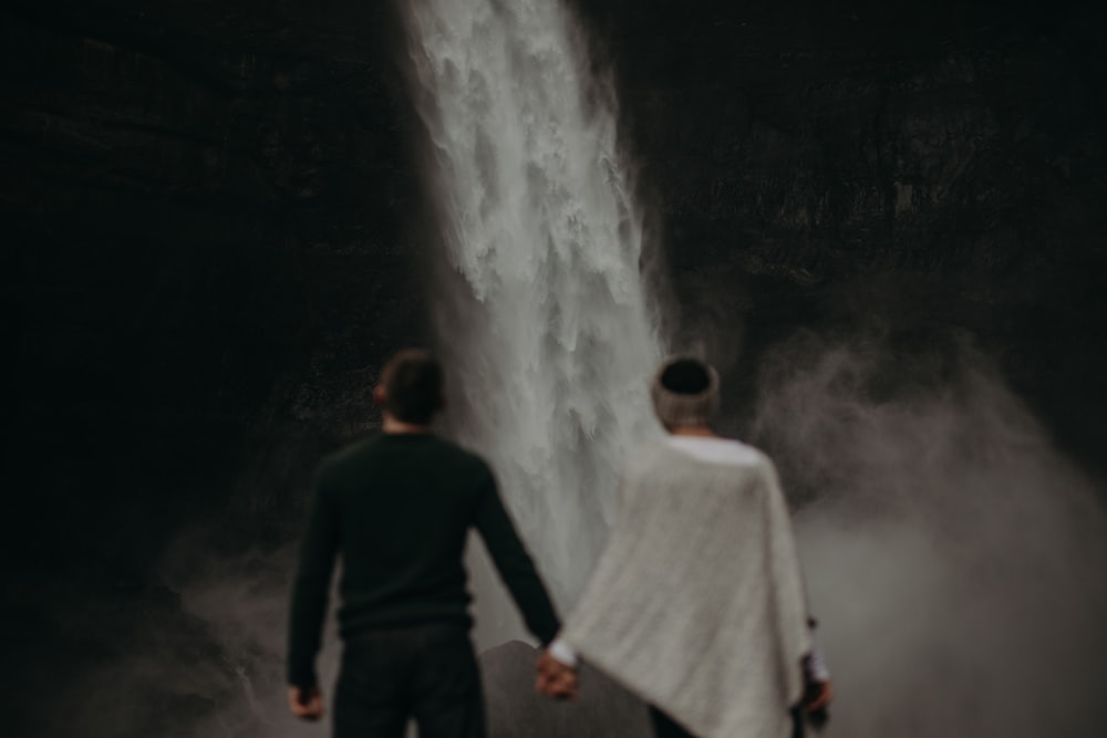 um homem e uma mulher em frente a uma cachoeira