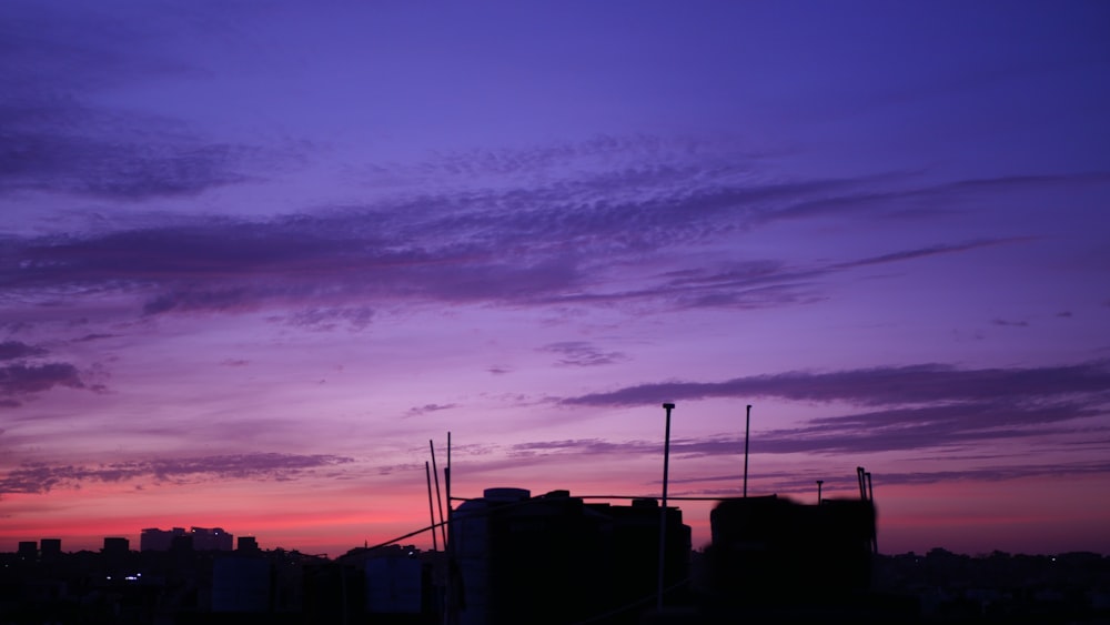 a purple sky with some clouds and some buildings